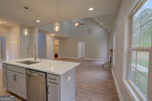 kitchen featuring stainless steel dishwasher, plenty of natural light, a center island with sink, and sink