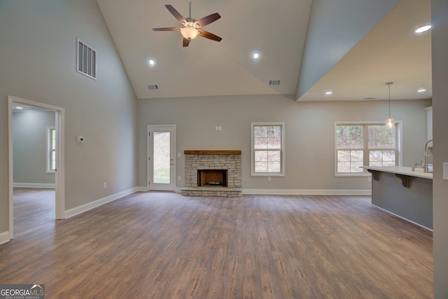 unfurnished living room featuring a fireplace, ceiling fan, dark hardwood / wood-style floors, and high vaulted ceiling