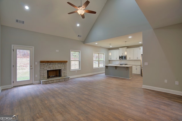 unfurnished living room with high vaulted ceiling, hardwood / wood-style flooring, ceiling fan, and a fireplace