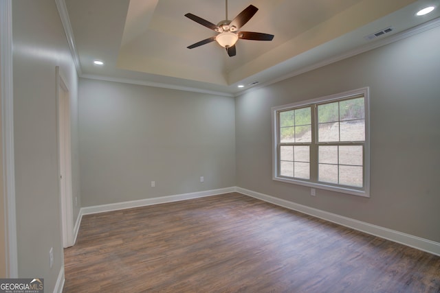 unfurnished room featuring ceiling fan, dark hardwood / wood-style floors, a raised ceiling, and crown molding