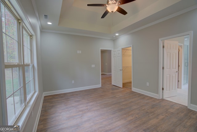 unfurnished bedroom featuring hardwood / wood-style flooring, ceiling fan, multiple windows, and a spacious closet