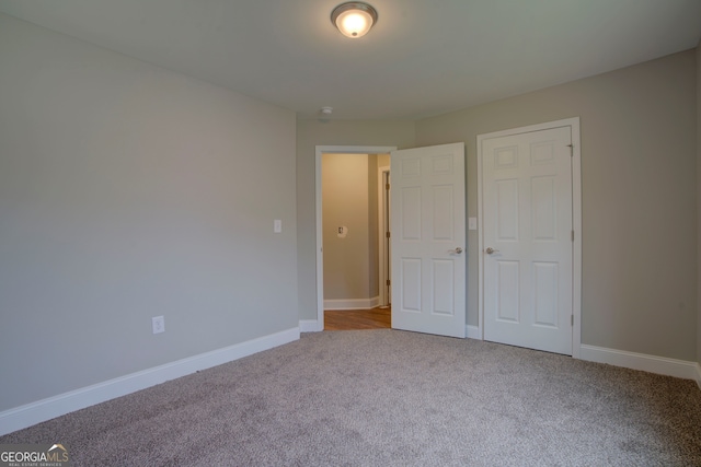 unfurnished bedroom with light carpet and a closet