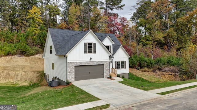 view of front of property with central air condition unit, a garage, and a front yard