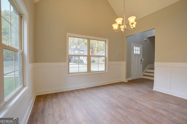 spare room with high vaulted ceiling, hardwood / wood-style flooring, and a chandelier