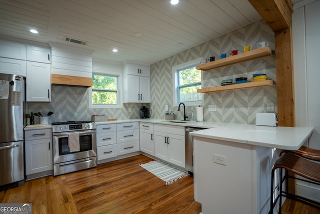 kitchen with dark hardwood / wood-style floors, white cabinetry, a healthy amount of sunlight, and appliances with stainless steel finishes