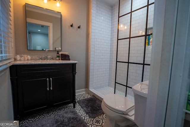 bathroom featuring toilet, tile patterned flooring, vanity, and a tile shower