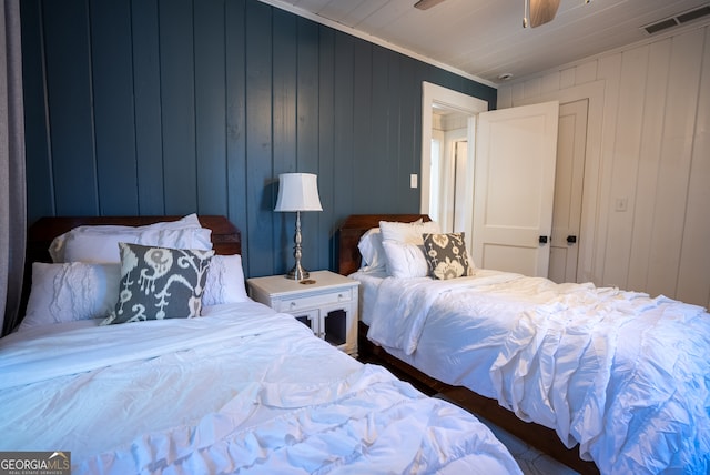 bedroom featuring wood walls, ceiling fan, and ornamental molding