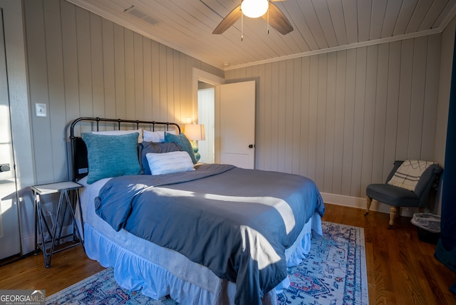 bedroom featuring wooden walls, ceiling fan, and dark hardwood / wood-style floors