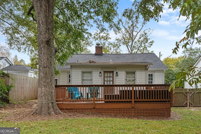 rear view of house featuring a lawn and a deck