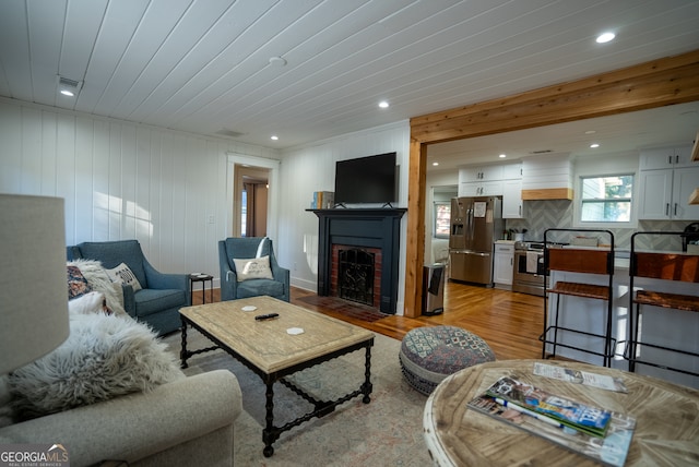 living room featuring light hardwood / wood-style floors, wood walls, and wooden ceiling