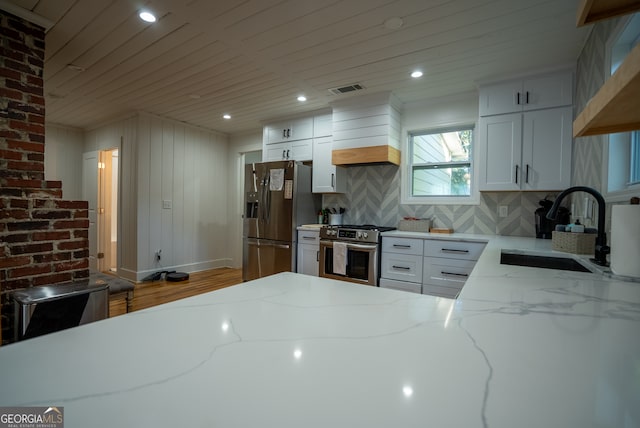 kitchen with white cabinets, stainless steel appliances, sink, and light stone countertops