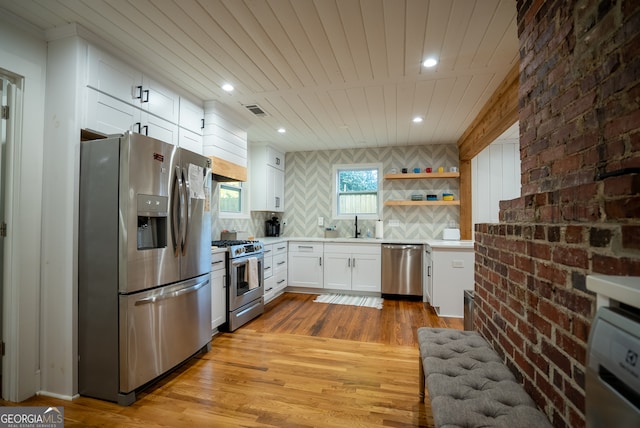 kitchen with stainless steel appliances, white cabinetry, backsplash, sink, and light hardwood / wood-style floors