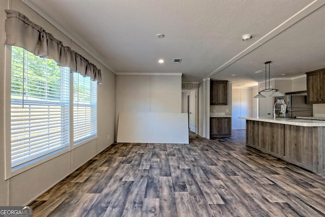 interior space featuring crown molding, decorative light fixtures, dark brown cabinets, dark hardwood / wood-style floors, and stainless steel fridge