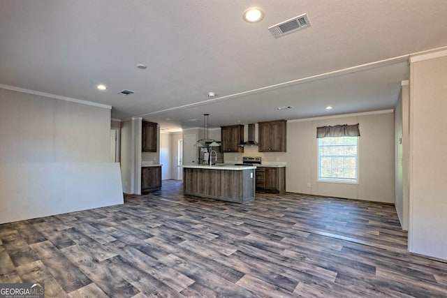 kitchen with sink, crown molding, dark wood-type flooring, a kitchen island with sink, and wall chimney exhaust hood