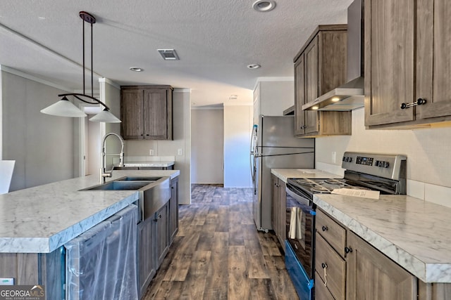 kitchen with sink, a kitchen island with sink, hanging light fixtures, stainless steel appliances, and wall chimney exhaust hood