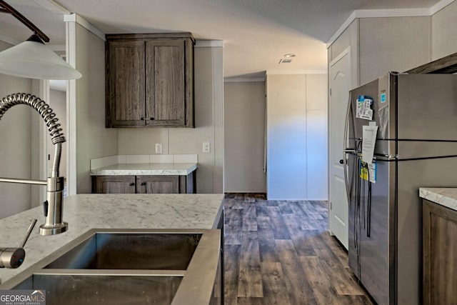 kitchen featuring sink, stainless steel refrigerator, dark brown cabinetry, light stone counters, and dark hardwood / wood-style flooring