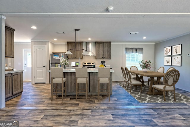 kitchen with a kitchen island, dark hardwood / wood-style floors, hanging light fixtures, stainless steel appliances, and wall chimney range hood