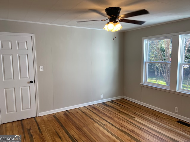 empty room featuring hardwood / wood-style floors, a wealth of natural light, ceiling fan, and crown molding