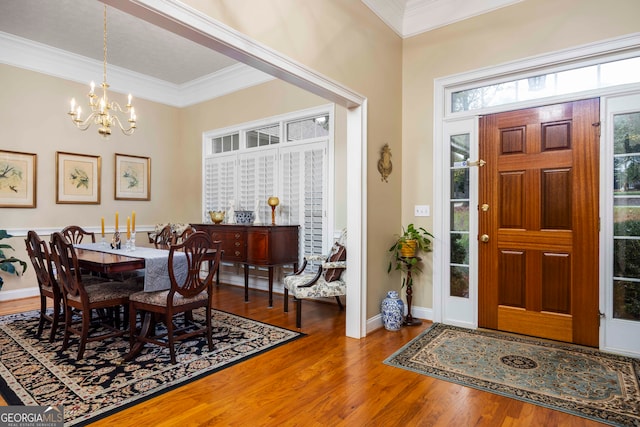 dining space with hardwood / wood-style floors, a chandelier, and crown molding