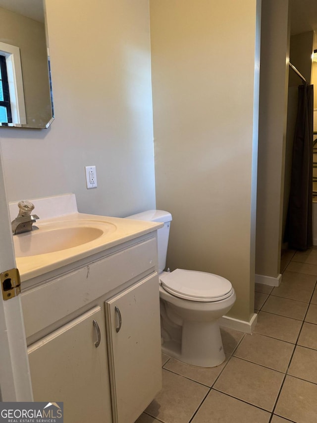 bathroom featuring toilet, walk in shower, vanity, and tile patterned floors