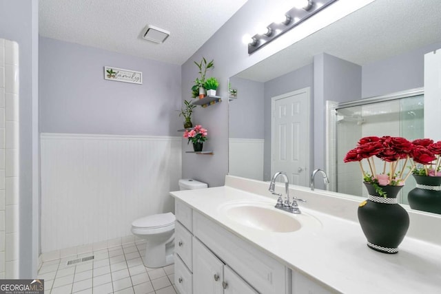 bathroom with tile patterned floors, vanity, a textured ceiling, an enclosed shower, and toilet