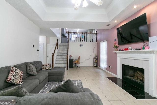 living room featuring a fireplace, tile patterned floors, and a tray ceiling