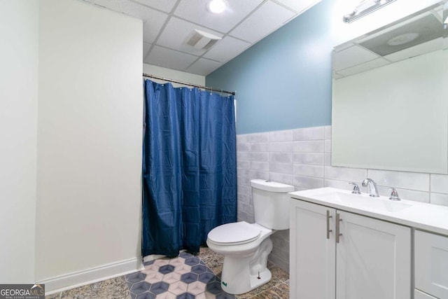 bathroom featuring tile walls, a paneled ceiling, toilet, and vanity