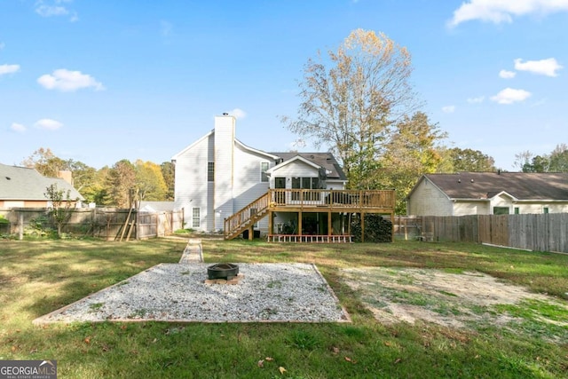 rear view of property with a yard, a wooden deck, and an outdoor fire pit