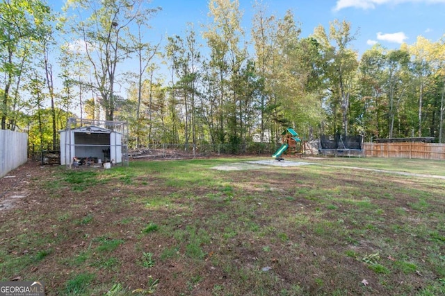 view of yard featuring a playground, an outdoor structure, and a trampoline