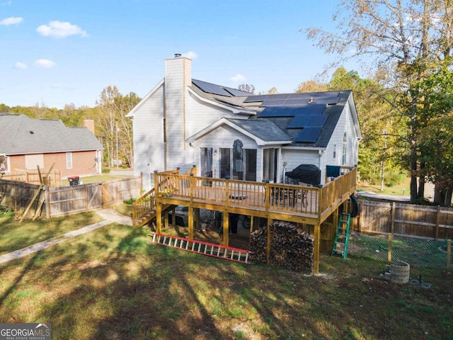 back of property featuring solar panels, a yard, and a deck