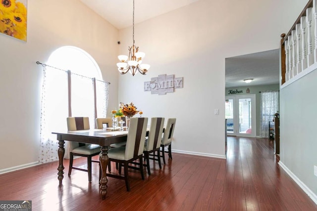 dining room featuring a high ceiling, a notable chandelier, dark hardwood / wood-style floors, and plenty of natural light