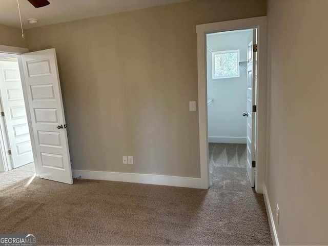 carpeted empty room with ceiling fan and baseboards