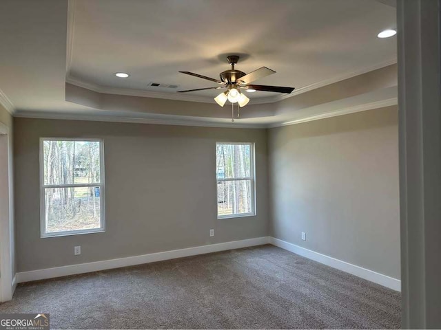 empty room with crown molding, a raised ceiling, carpet flooring, ceiling fan, and baseboards