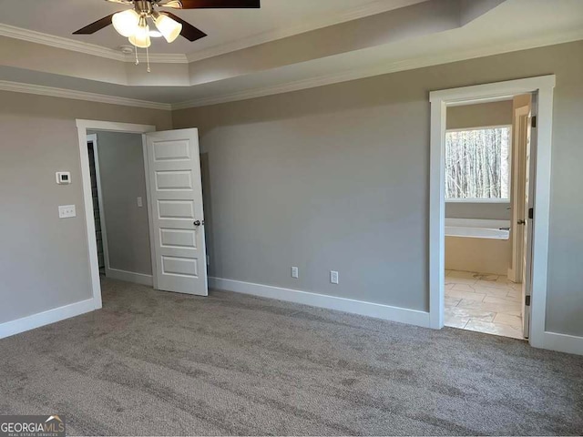 unfurnished bedroom with ornamental molding, a raised ceiling, carpet flooring, and baseboards