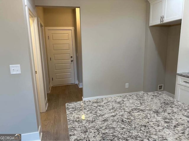 interior space featuring dark wood-style flooring, white cabinets, baseboards, and light stone countertops