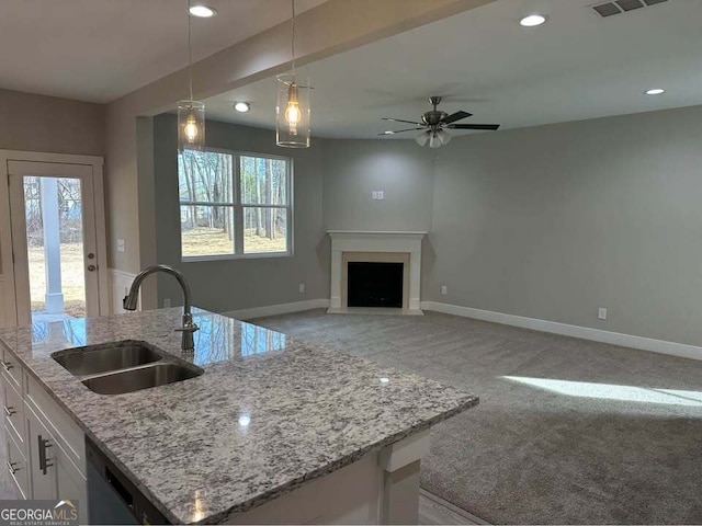 kitchen featuring light carpet, a sink, white cabinetry, and baseboards