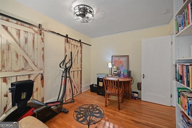 exercise room with light hardwood / wood-style floors and a barn door