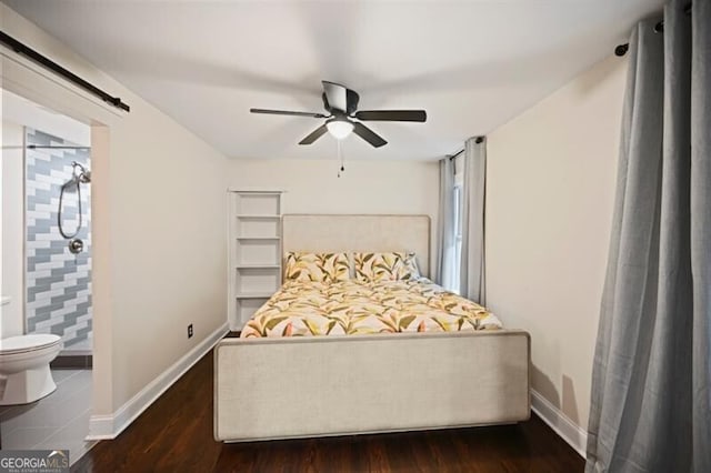 bedroom featuring ensuite bathroom, a barn door, dark hardwood / wood-style floors, and ceiling fan