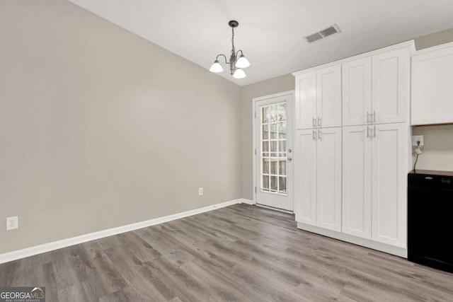 unfurnished dining area with light hardwood / wood-style floors and a notable chandelier