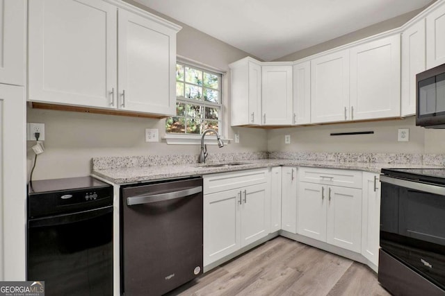 kitchen featuring stainless steel appliances, white cabinetry, sink, light stone countertops, and light wood-type flooring