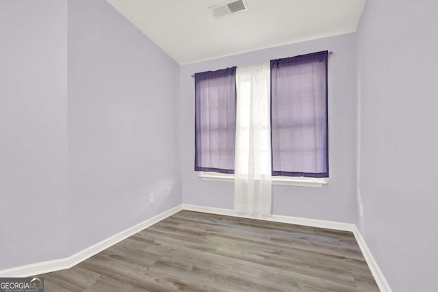 spare room with hardwood / wood-style flooring and vaulted ceiling