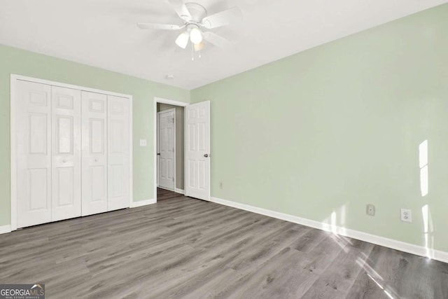 unfurnished bedroom featuring a closet, wood-type flooring, and ceiling fan