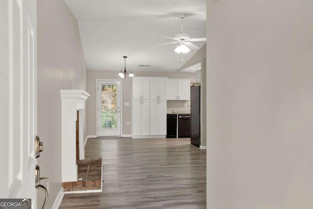 unfurnished living room featuring lofted ceiling, hardwood / wood-style flooring, and ceiling fan with notable chandelier