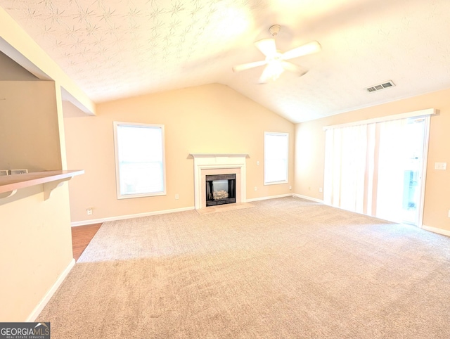 unfurnished living room with a wealth of natural light, lofted ceiling, ceiling fan, and carpet floors