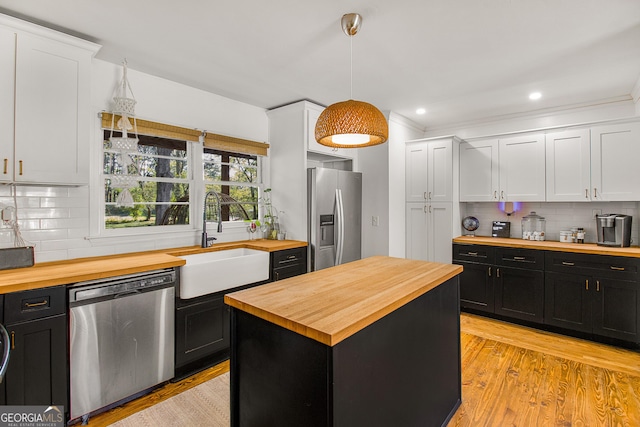 kitchen featuring sink, a center island, wood counters, white cabinets, and appliances with stainless steel finishes