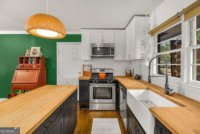 kitchen with white cabinetry, stainless steel appliances, dark hardwood / wood-style floors, butcher block countertops, and pendant lighting