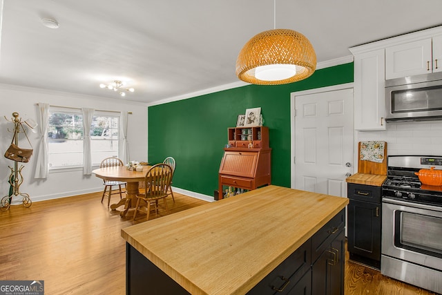 kitchen featuring decorative backsplash, appliances with stainless steel finishes, light wood-type flooring, pendant lighting, and a kitchen island