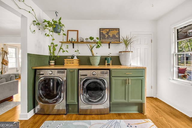 washroom featuring washer and clothes dryer, light hardwood / wood-style floors, and cabinets