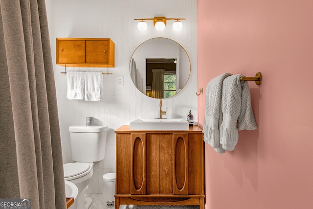 bathroom featuring vanity, a bidet, tile walls, and toilet