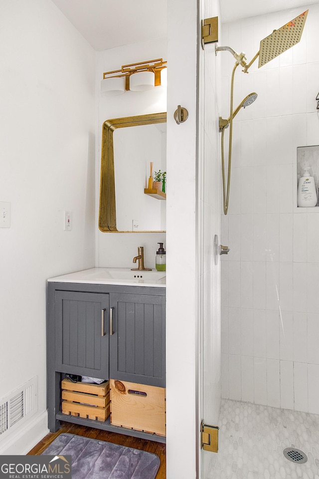 bathroom with hardwood / wood-style flooring, vanity, and an enclosed shower